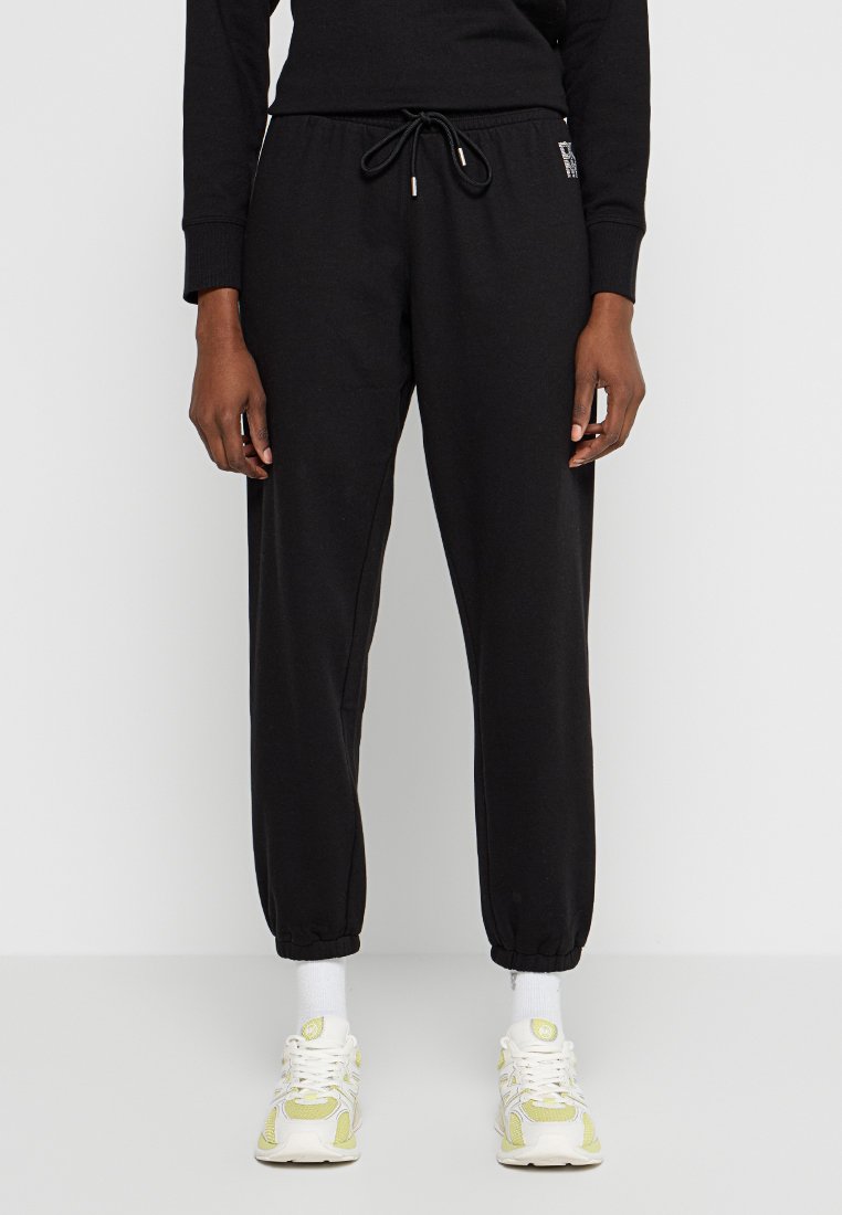 Czarne dresy wykonane z miękkiego materiału, z elastycznym paskiem w talii z troczkiem, zwężającymi się mankietami i kieszeniami bocznymi.