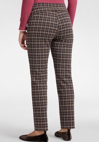 Spodnie w kratę w ciemnym niebieskim, brązowym i kremowym kolorze. Slim-fit z średnim stanem i gładką fakturą. Płaski przód, długość do kostek.