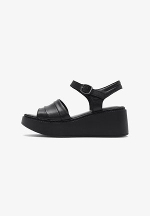 Sandales à plateforme noires avec un dessus en cuir texturé, orteil ouvert et sangle de cheville réglable. Équipées d'un épais talon compensé et de détails cousus.