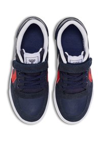 Marineblauwe sneakers met een bovenkant van suede en mesh, met witte accenten en een rode chevronafwerking, vastgemaakt met veters en een klittenbandsluiting.