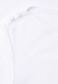 Hvid bomuldstop med rund halsudskæring og to hvide knapper på skulderen. Glat tekstur med et enkelt design.