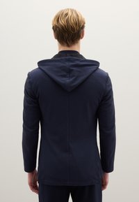 Felpa con cappuccio blu navy dal design aderente, maniche lunghe e schiena ventilata. Presenta una texture morbida con un colletto nero a contrasto.