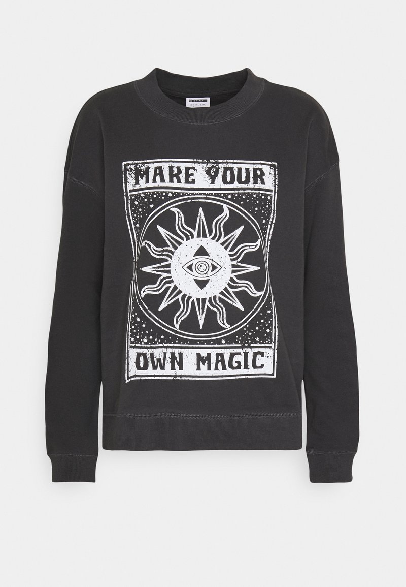 Sweat-shirt noir avec un motif blanc de soleil et d’œil et le texte "Make Your Own Magic" sur le devant.