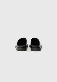 Sorte slip-on sko med en jevn finish, rund tå og lav hæl. Enkelt design uten synlige mønstre eller spor av maskinvare.