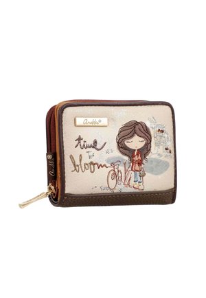 Pequeña cartera beige y marrón con una niña bordada, bicicleta y texto "travel to bloom" en la parte delantera con cremallera dorada y etiqueta.