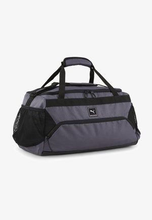 Sac de sport gris avec des accents noirs, fabriqué en tissu durable. Comprend des poches latérales en maille, des poignées doubles et un compartiment principal zippé.