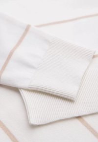 Witte stof met lichtbeige strepen, voorzien van geribde boorden en een gladde textuur. Het ontwerp benadrukt eenvoud en subtiele details.