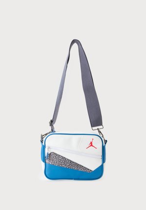 Mała prostokątna torba na ramię w kolorze białym i niebieskim z szarym regulowanym paskiem i czerwonym logo Jumpman na przedniej kieszeni.