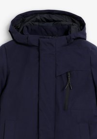 Marineblauwe hooded jacket met een gladde buitenkant, een ritszak en versterkte stiksels. Beschikt over een hoge kraag en een gestroomlijnd ontwerp.