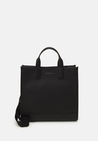 Bolso tote de cuero negro con superficie texturizada, asas superiores y correa para el hombro desmontable. Presenta un detalle del logo en la parte frontal.