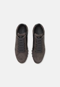 Zapatillas de ante gris oscuro con detalles en cuero negro, que cuentan con seis ojales y suelas de goma texturizadas. Los cordones lisos y planos completan el diseño.