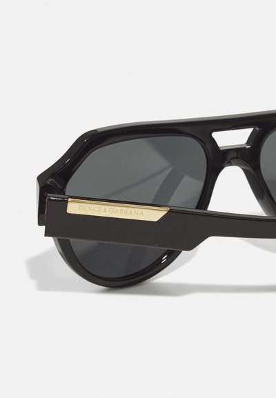 Black sunglasses with rectangular lenses, featuring thick frames and a gold accent on the temple, branded with "DOLCE & GABBANA."