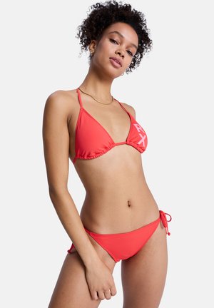 Červená súprava bikín s trojuholníkovým vrškom a spodným dielom so zaväzovaním na bokoch. Vyrobené z hladkej tkaniny, obsahuje nariasené šitie a výrazné logo na vršku.