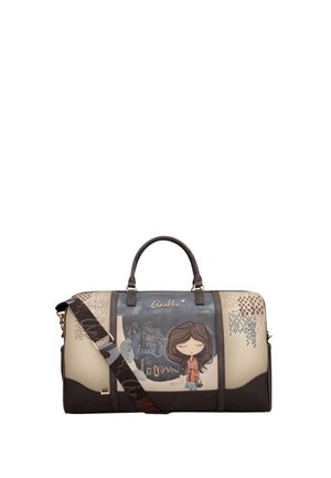 Beige und braune Reisetasche mit einer Illustration eines Cartoon-Mädchens, goldenem "Anekke"-Logo und einem dunklen verstellbaren Schulterriemen mit Textmustern.