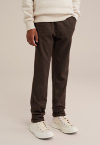 Bruna texturerade byxor med avslappnad passform, som har framfickor och ett subtilt mönster. Matchas med vita kanvas-sneakers.