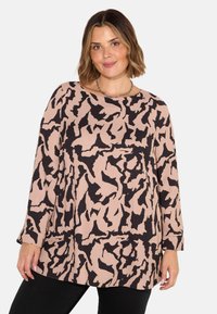 Blusa a maniche lunghe beige con un motivo astratto nero, dotata di scollo rotondo e vestibilità leggermente ampia. Tessuto morbido, stile casual.