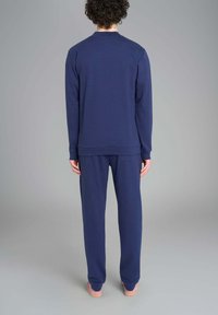 Completo loungewear in cotone blu navy composto da una maglietta a maniche lunghe con scollo rotondo e pantaloni abbinati. Design semplice, vestibilità rilassata, senza motivi o dettagli visibili.