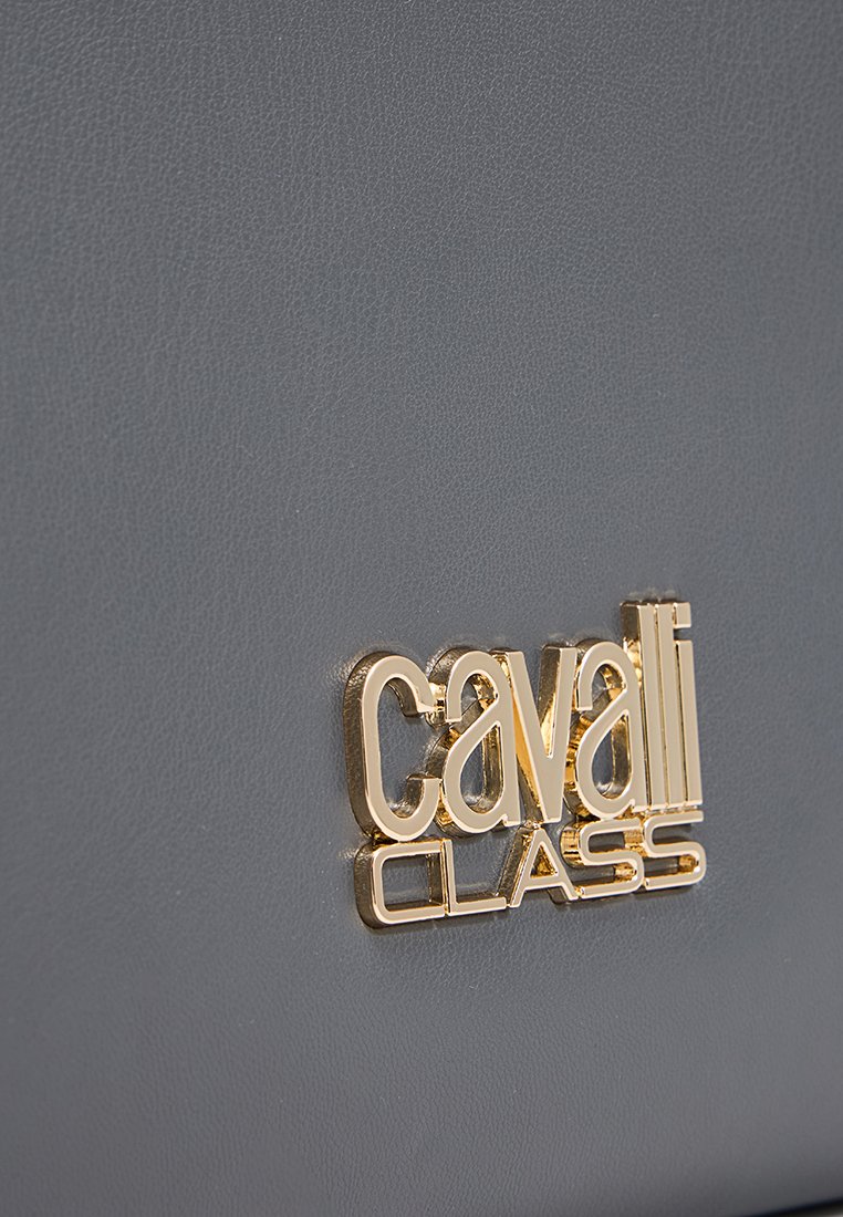 Złote logo "cavalli CLASS" na gładkiej szarej skórze, podkreślające szczegóły marki i teksturę materiału.