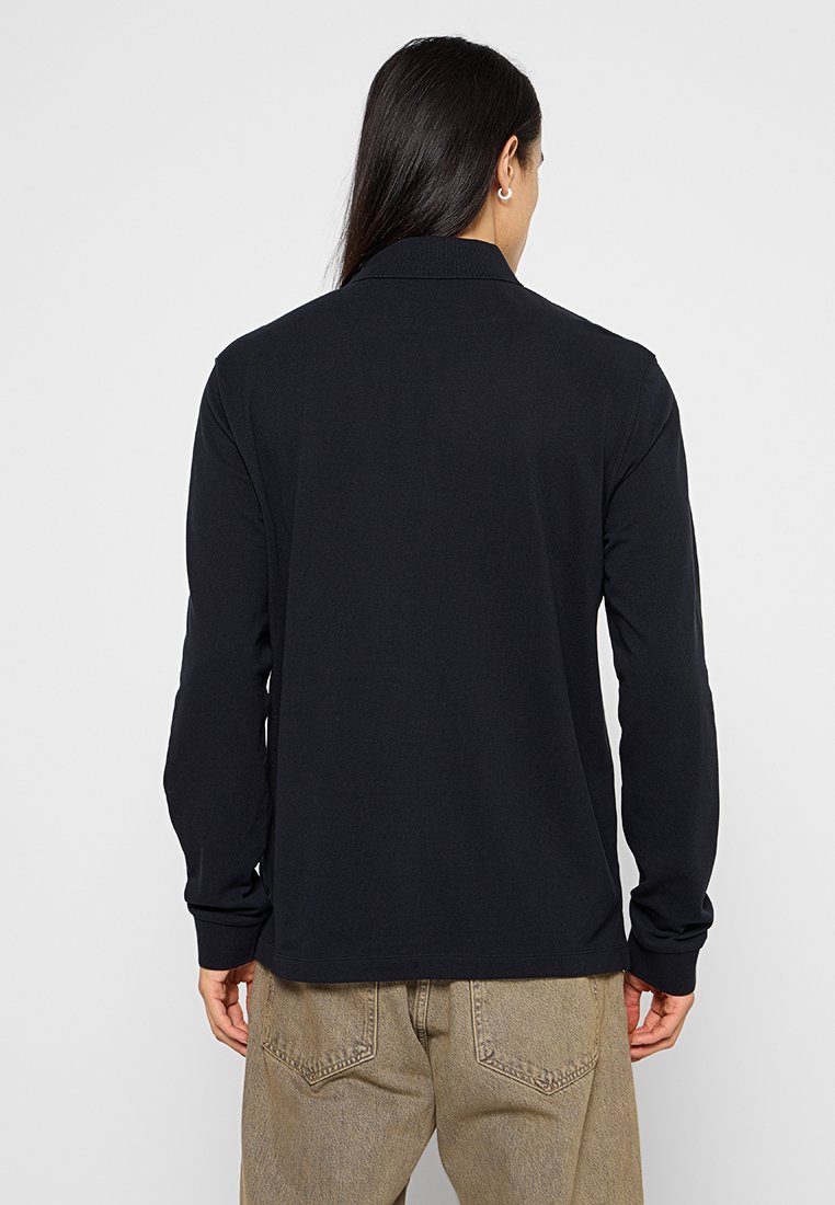 Schwarzes Langarm-Polohemd mit Kragen, aus weichem Baumwollmaterial; Rückansicht zeigt glatte Textur und taillierte Passform.