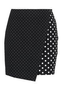 Černá obalová sukně vyrobená z texturované látky s diagonálním vzorem. Pravá strana má bílý puntíkovaný vzor.