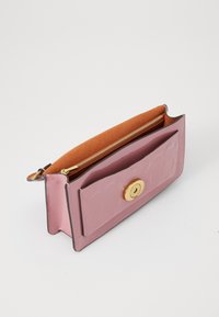 Rosa lackläderplånbok med guldhårdvara, med en enfärgad design, ett dragkedjeutrymme och ett präglat mönster på framsidan.