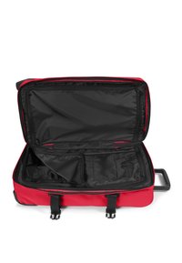 Maleta roja con interior negro. Presenta una apertura con cremallera, compartimentos internos y dos hebillas para asegurar el contenido.