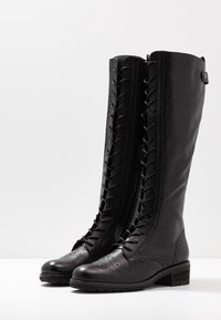 Svarta läderknähöga stövlar med broguedetaljer, snörning framtill, rund tå, texturerad sula och en liten klack.