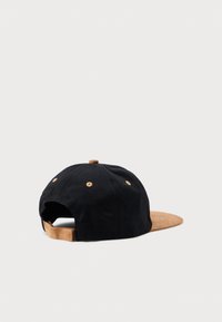 Cappello di cotone nero con visiera in suede marrone, dotato di sei occhietti ricamati e di una fascia regolabile sul retro.