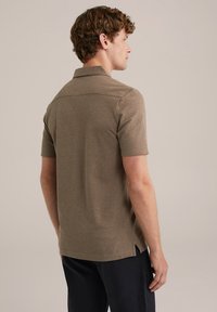 Cămașă polo scurtă, de culoare maro, dintr-un material texturat, cu guler și fante laterale; design simplu, fără modele sau accente.