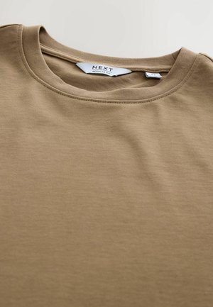 Pruun puuvillane T-särk, millel on ümmargune kaelus ja lühikesed varrukad. Sellel on "NEXT" logo sisetagal, sile tekstuur ja regulaarne lõige.