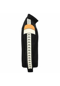 Chaqueta negra con cremallera y acentos en naranja y crema en los hombros. Presenta franjas laterales blancas con logotipos y puños y dobladillo acanalados. Textura de tela suave.