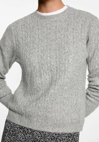 Šedý pletený svetr s texturovaným kabelkovým vzorem. Hladký kulatý výstřih a manžety. Měkký materiál, těsně padnoucí silueta a klasický design.