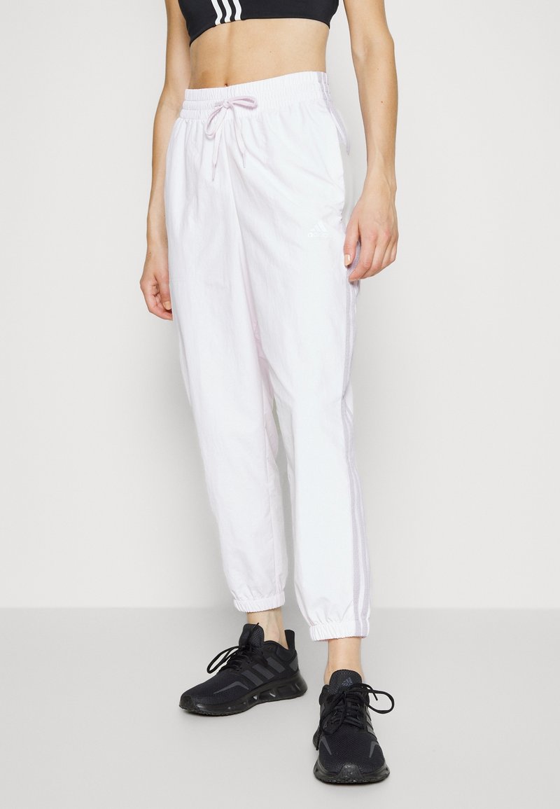 Vita idrottsbyxor med elastisk midja och dragsko. Har smalnande mudd. Kombination med svarta idrottsskor.