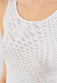 Witte mesh tanktop met een ronde halslijn en een klein logo detail. Het materiaal is licht en ademend met een gestructureerd oppervlak.