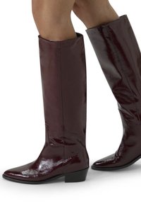 Burgundy knee-high boots in glossy finish, featuring a pointed toe and low block heel, with a smooth patent leather texture.