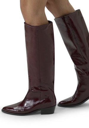 Burgundy knee-high boots in glossy finish, featuring a pointed toe and low block heel, with a smooth patent leather texture.