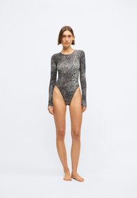 Bodysuit de manga longa com estampa de leopardo e pernas de corte alto, apresentando um tecido liso e elástico em tons de cinza e preto, com um design ajustado.