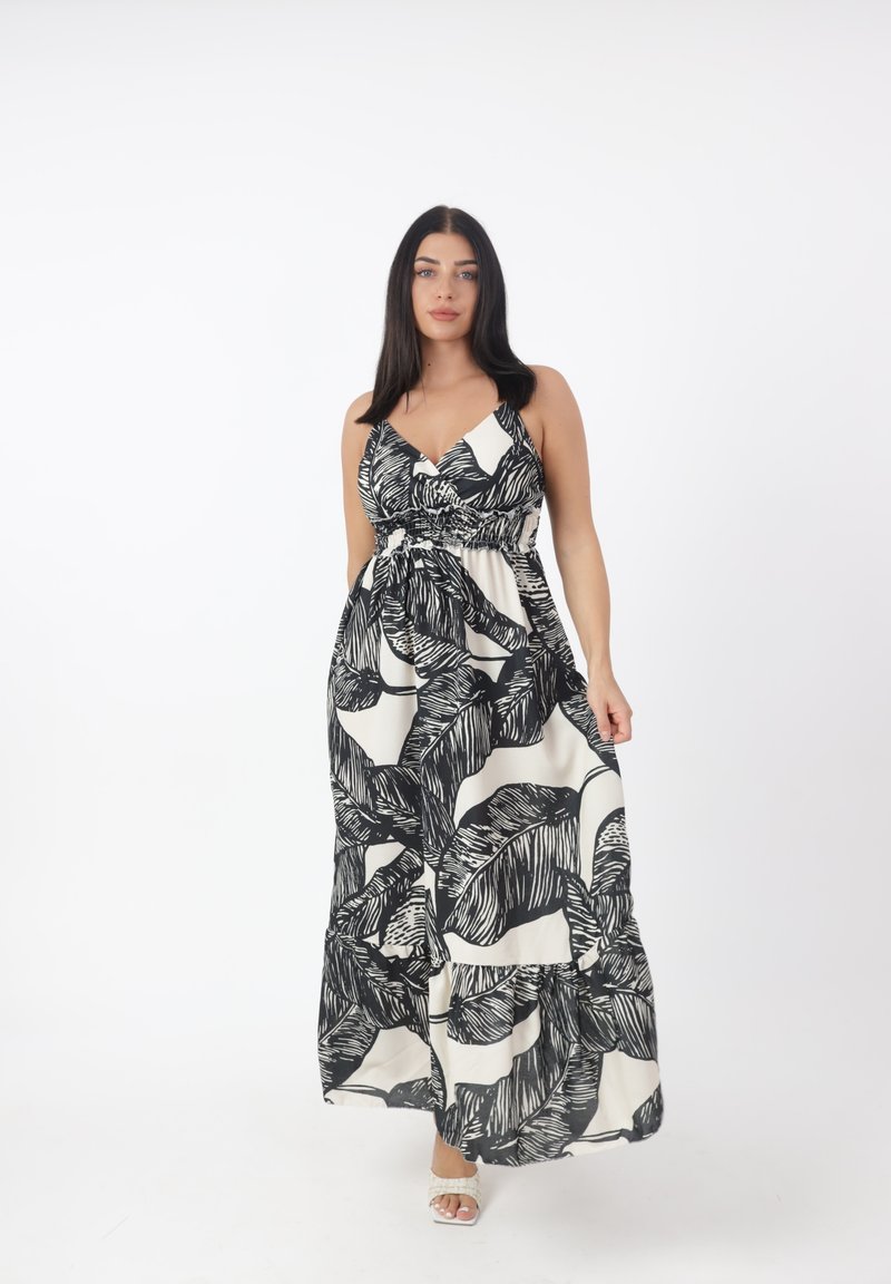 Robe maxi avec un motif de feuilles noires sur un fond crème. Présente un corsage ajusté et une jupe évasée avec un ourlet en tiers. Bretelles réglables.