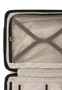 Interno di una valigia nera con zip, dotata di un separatore in rete con motivo esagonale e cinghie elastiche incrociate, foderato in tessuto beige chiaro.