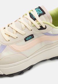 Sneakers bej cu materiale din plasă și cauciuc, având accente roz și violet, sireturi rotunde și o talpă neagră cu șanțuri proeminente.