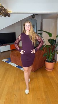 Mauve long-sleeve dress with lace detailing, form-fitting silhouette, worn with light-colored flats, set in a room with plants and furniture.