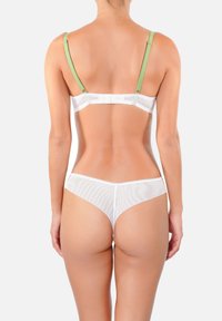 Ensemble de lingerie blanche avec un design en mesh transparent, des bretelles réglables vert clair, une fermeture au dos et un style de string minimaliste.