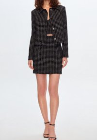 Zwart-wit geruit blazer- en rokkenset, met een cropped ontwerp, gestructureerde stof en metalen knoopaccenten.