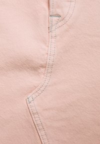 Tessuto rosa chiaro con una trama tessuta, caratterizzato da una cucitura curva e da cuciture in azzurro chiaro a contrasto. Nessun motivo o hardware visibile.