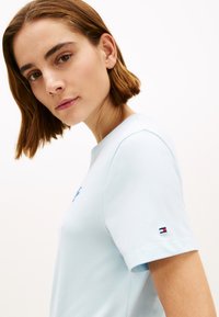 T-shirt en coton bleu clair à manches courtes, avec un logo brodé sur le devant et un petit accent de logo sur la manche.
