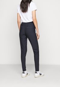 Marina randiga byxor med elastisk midja, smal passform och två bakfickor, kombinerade med vita sneakers och en enkel vit t-shirt.