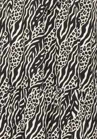 Tissu à motif animalier abstrait en noir et blanc avec des rayures semblables à celles d'un zèbre et des taches semblables à celles d'un léopard, légèrement froncé au niveau d'une couture.