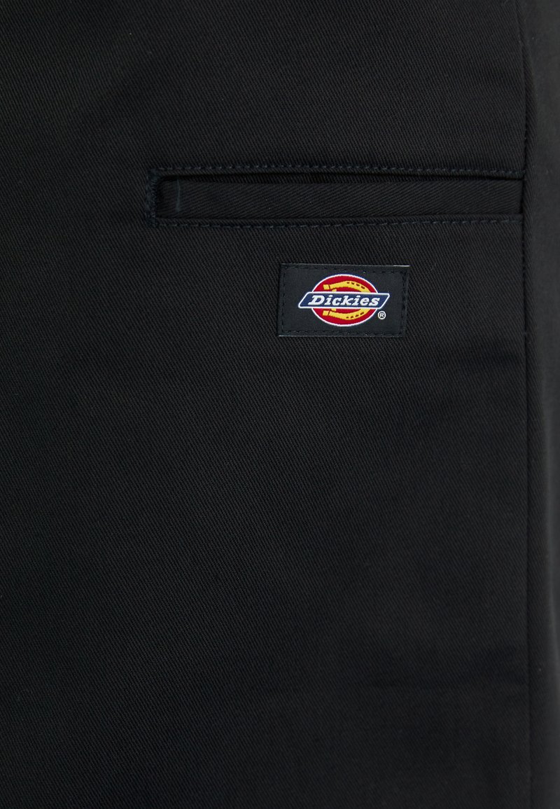 Tessuto nero con una leggera texture, dotato di una tasca posteriore e di un'etichetta colorata del marchio Dickies cucita sul tessuto.