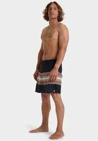 Ανδρικά μαγιό θαλάσσης σε ναυτικό μπλε με οριζόντια ριγέ σχέδια σε μπεζ, κόκκινο και ελιά. Διαθέτουν ελαστική μέση με κορδόνι και πλαινές τσέπες.