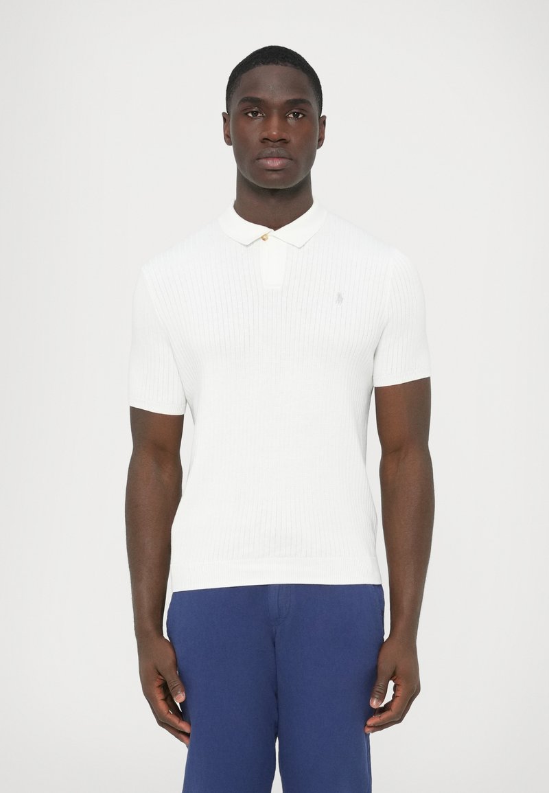 Biele rebrované krátke rukávy polo tričko s golierom a malým logom na ľavej strane hrudníka. Materiál pôsobí hladko a priliehavo.